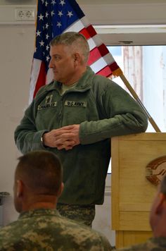 a man standing at a podium in front of an american flag