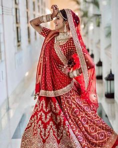 a woman in a red and gold bridal gown posing for the camera with her hands on her head