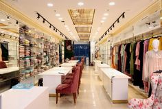 the inside of a clothing store filled with lots of chairs and tables in front of them