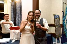 two people standing next to each other holding drinks