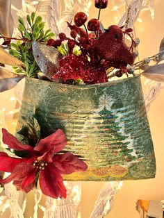 a vase filled with red flowers on top of a table next to a christmas tree