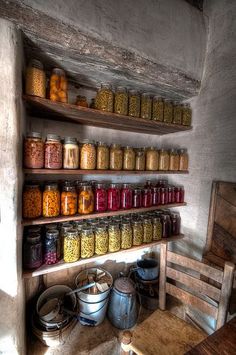 an old kitchen filled with lots of jars and pans on top of wooden shelves