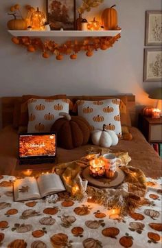 a bed with pumpkins and candles on top of it next to an open book