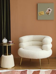 a white chair sitting next to a table with a clock on it