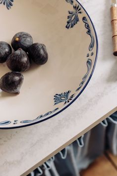 some black figs are in a blue and white bowl