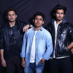 three men standing next to each other in front of a black background wearing leather jackets