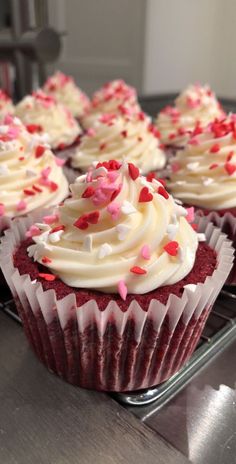 red velvet cupcakes with white frosting and sprinkles on a cooling rack