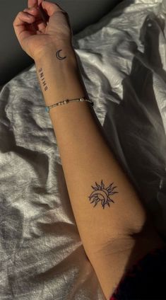 a woman's arm with a small sun and moon tattoo on her left arm