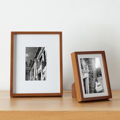 two framed photographs sitting on top of a wooden table