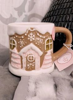 a coffee mug with a gingerbread house on it and a tag hanging from the handle