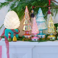 an assortment of glass christmas trees on a mantel