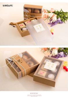 two boxes with different types of chocolates in them on a white table next to flowers