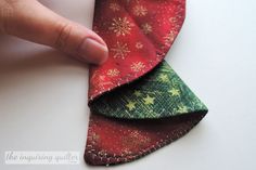 a hand is holding an ornament on top of a piece of fabric that has been sewn together