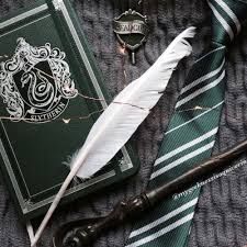 a harry potter book, tie, and quill - pen on a bed sheet