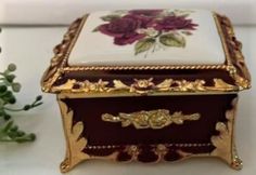 an ornately decorated box sitting on top of a white table next to some flowers