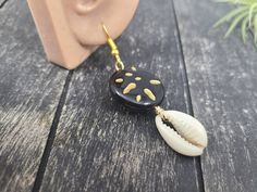 "These gorgeous dangle earrings feature genuine off-white sliced moneta cowrie shells dangling beneath 20mm round carved black and gold acrylic beads an etched Afrocentric abstract pattern. Aching for acrylics? Check out the rest of my acrylic jewelry here: https://etsy.me/2IadiWZ Throughout Africa and the Americas, cowrie shells have historically been viewed as symbols of womanhood, fertility, and prosperity. Check out my other cowrie shell jewelry here: https://etsy.me/2VQS0r0 These earrings m Black Dangle Jewelry For Beach, Black Shell Jewelry For Gifts, Black Shell Jewelry Gift, Black Shell Jewelry As A Gift, Unique Black Beach Jewelry, Handmade Black Jewelry For Vacation, Black Shell Bohemian Jewelry, Handmade Black Earrings For Beach, Handmade Black Shell-shaped Jewelry