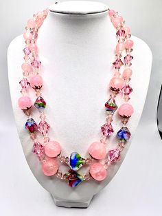 This vintage necklace is a stunning piece of art that will elevate any outfit. It features two strands of pink lucite and art glass beads, along with AB rondelle beads for added sparkle. The necklace has a beautiful multicolor main stone and is perfect for women who love beaded jewelry with an artistic touch. Crafted from high-quality glass and lucite materials, this necklace is a unique addition to any jewelry collection. Its country of origin is unknown, but its beauty is undeniable. Whether you're dressing up for a formal occasion or adding a touch of vintage flair to your everyday look, this necklace is sure to make a statement. Pink Glass Jewelry With Faceted Beads, Pink Glass Jewelry With Colorful Beads, Vintage Pink Czech Glass Jewelry, Pink Adjustable Beaded Necklaces For Costume Jewelry, Pink Adjustable Costume Jewelry Necklaces, Pink Adjustable Costume Jewelry Necklace, Pink Czech Glass Necklaces With Faceted Beads, Handmade Pink Double Strand Necklaces, Pink Handmade Double Strand Necklaces