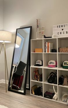 a large mirror sitting on top of a white shelf next to a lamp and purses