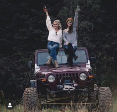 two women are sitting on top of a jeep