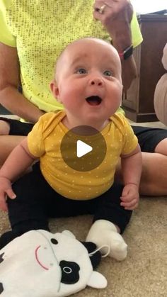 a baby is sitting on the floor next to a stuffed animal and smiling at someone