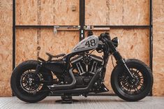 a black motorcycle parked in front of a wooden wall with the number forty on it