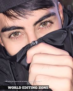 a man with black hair is covering his face and looking at the camera while wearing glasses