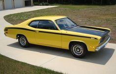 a yellow and black car parked on the side of a road in front of a garage