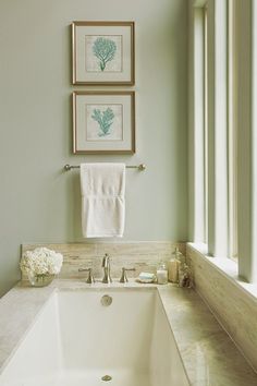 a bathroom with two pictures hanging above the bathtub