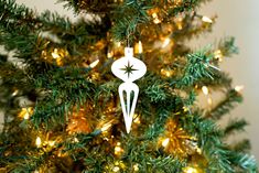 a white ornament hanging from the top of a christmas tree with lights on it