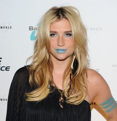 a woman with blue lipstick on her face and long blonde hair, posing for the camera