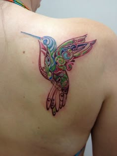 the back of a woman's shoulder with a hummingbird tattoo on her left side