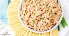 a white bowl filled with tuna dip surrounded by crackers and celery sticks