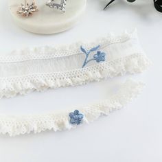 Beautiful white Wedding garters made with elastic lace and tiny blue embroidered flowers. Custom sized just for you and comes in a gift box. The keepsake garter measures 1 5"8" wide and the toss 5/8".  MEASURING INSTRUCTIONS: Use a soft tape measure or string and ruler. Measure where you want to wear your keepsake (the larger) garter. Measure a bit snug, not too tight or too loose. Order your actual measurement and I will take some off so it stretches to fit. The toss garter will be made smaller than the keepsake. SHIPPING: Each item is custom handmade to order and will ship out 3-5 business days after you order. Then shipping takes another 2-5 days. Most orders in the USA arrive 8-10 days after the order date, but allow up to 2 weeks. If you need it sooner than 2 weeks, add the rush fee s Bridal Garter Blue, Wedding Garter Blue, Blue White Weddings, Blue Garter, Wedding Garters, Bridal Garter, Wedding Garter, Wedding Mood Board, Elastic Laces