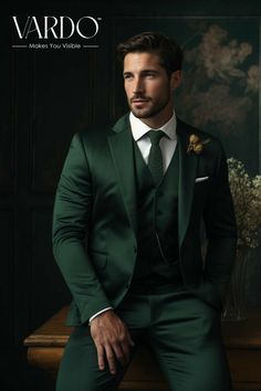 a man in a green suit sitting on a wooden table wearing a white shirt and tie