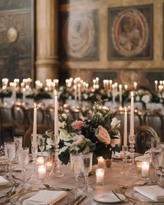 the table is set with candles and flowers in vases, plates and silverware