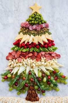 a christmas tree made out of grapes, nuts and meats on a marble surface