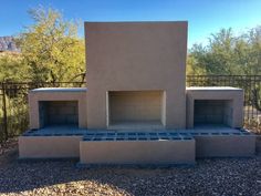 an outdoor fireplace built into the side of a building with rocks and gravel around it