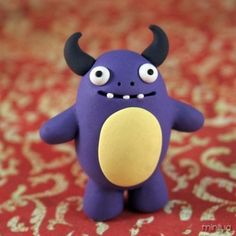 a purple toy with horns and eyes sitting on a red carpeted area next to a rug