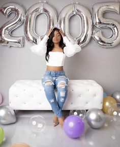 a woman sitting on top of a couch in front of balloons and letters that spell 205