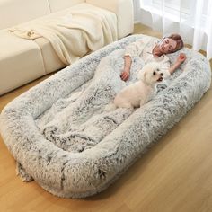 a woman laying on top of a fluffy dog bed