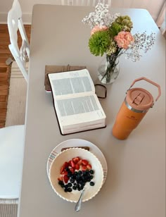 a bowl of berries and yogurt next to an open book on a table