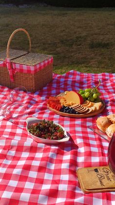 a picnic blanket with food on it and wine glass sitting next to the table in front of it