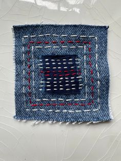 a piece of blue fabric with red and white stitchs