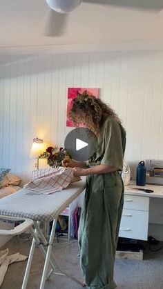 a woman standing in front of a ironing board on top of a white table