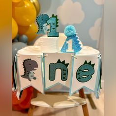 a table with some decorations on it and balloons in the background, including one birthday cake