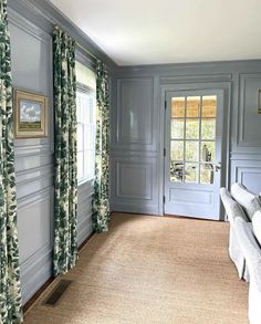 a living room with blue walls and curtains on the windowsills, carpeted floor