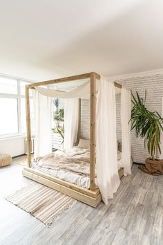 a bedroom with white walls and wood flooring has a four poster bed in the corner