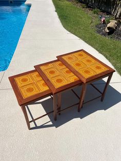 two wooden tables sitting next to a swimming pool