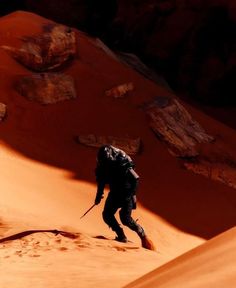 a man hiking up the side of a sand dune