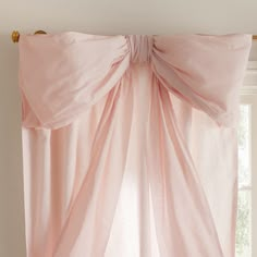 a pink curtain hanging on the side of a window